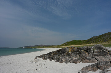 Fototapeta na wymiar Prince's Beach or Prince's Strand on Eriskay, Outer Hebrides, Scotland. White sand, turquoise blue water, rocks, hills, blue sky and light cloud. Sunny day, no identifiable people. Copy space.