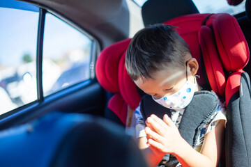Young Asian Boy Praying in car seat
