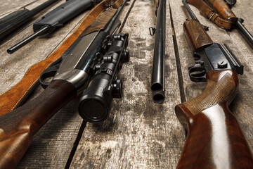 Many hunting rifles on weathered wooden surface