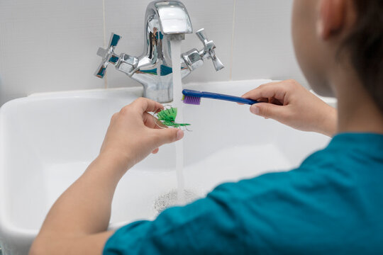 Boy is cleaning his dental orthodontic plates with toothbrush, hygiene procedure for keeping plates clean and safe for daily usage.