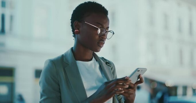 Beautiful black young tourist girl using smartphone online navigation map browsing application making her way in modern city downtown.