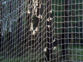 The old ragged net of football goals is illuminated by the sun. Rope mesh background.