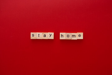 word STAY HOME made of wooden letters on red background with copy space