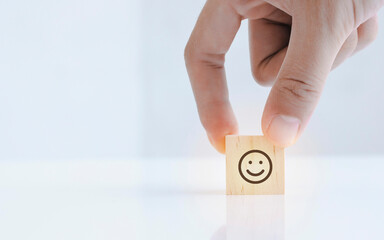 Close up of hand customer hand choose a smiley face icon on the wood cube, Service rating,...