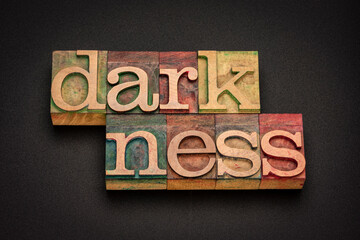 darkness word abstract in vintage letterpress wood type against black background, total absence of light
