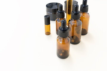 Glass bottles for essential oil, lotion or serum on a pastel beige background. Reusable containers. Zero waste, eco friendly concept. Dark amber glass bottles. Layout of the beauty salon branding