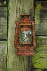 Stara lampa naftowa na drewnianym ogrodzeniu, ścianie . Old, kerosene lamp hanging on a wooden...