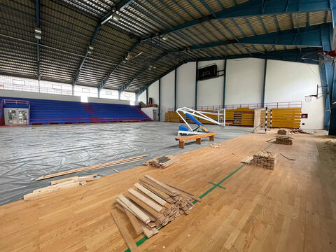 Construction site of sports hall, basketball court renovation, school gym indoor changing hardwood parquet flor and insulation.