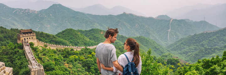 Travel couple China tourists at view of Great wall mountains landscape. Happy interracial Caucasian man, Asian woman enjoying famous destination at Beijing city. Asia summer vacation banner panoramic.