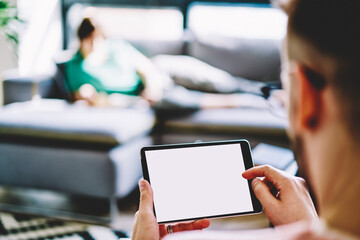 Cropped male blogger browsing web advertising on mockup gadget with copy space area for your text, millennial man making online booking and banking via touch pad application with blank screen