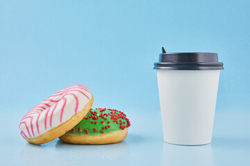Sweet donut or doughnut with hot cup of fresh brewed coffee or tea. Takeaway paper cup with donuts. Breakfast at the coffee shop concept.