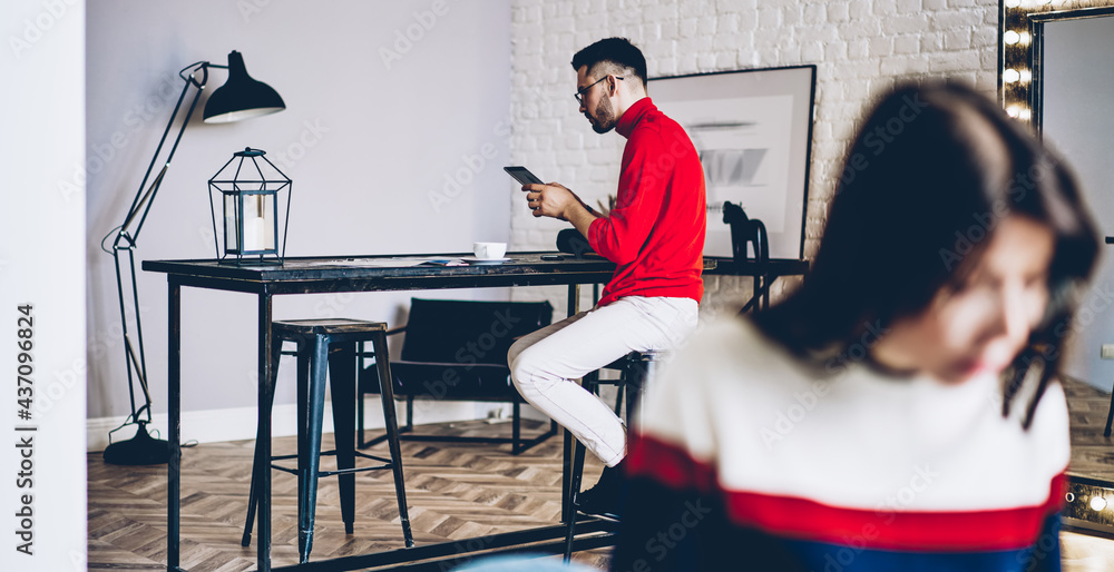 Poster caucasian hipster guy using touch pad gadget for checking web information during weekend time in hom