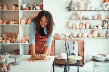 Cheerful young woman working in pottery workshop - obrazy, fototapety, plakaty