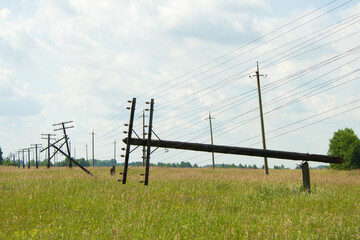 Two wooden poles of the power line broke and fell. The communication line goes into the distance....