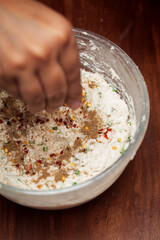 Close-up of Preparation of  dahi vada - mixture of grind urad dal with condiments and ingredients and roasted cumin and green fresh coriander for preparation of chaat.