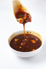 Close-up of mango dry fruits sweet red dark chutney used in Indian chaat and fast food in white ceramic bowl.