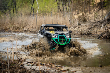 Fototapeta na wymiar Cool view of active 4x4 vehicle driving in mud and water. ATV rider