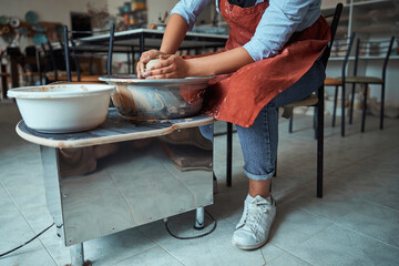 Female ceramist throwing earthenware pot on pottery wheel