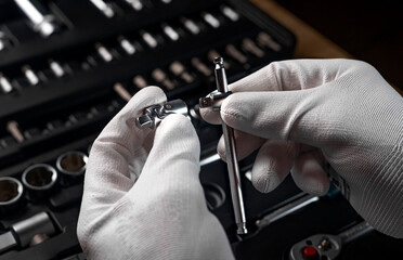 Male hands in gloves over open toolbox with different metal tools for car and home repair, close up.