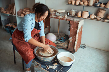 Charming female ceramist making pottery in workshop