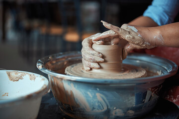 Female hands throwing clay pot on pottery wheel