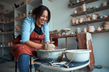 Cheerful female potter making pottery in workshop - obrazy, fototapety, plakaty