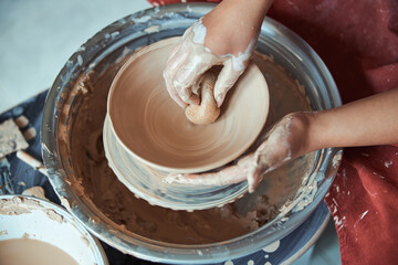 Female potter hands wiping clay bowl with sponge