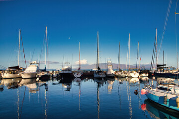 Fototapeta na wymiar View of the lahaina harbor at dawn with setting moon and lanai in the distance