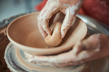 Female ceramist hands wiping clay bowl with sponge