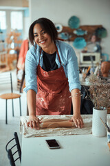 Joyful craftswoman in apron working in pottery workshop