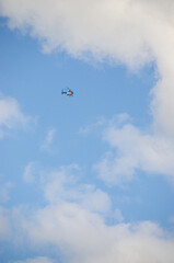 A police helicopter hovering against a light blue sky and feather clouds