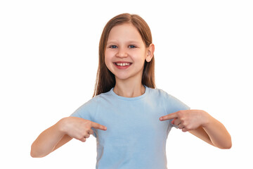 The little girl points her fingers at her chest. A smiling child points to her T-shirt