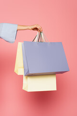 Cropped view of female hand holding shopping bags isolated on pink