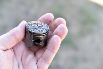 A small piston in the hand from an internal combustion engine