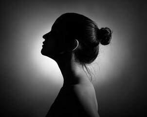 Silhouette of a beautiful young woman in profile on a dark background.
