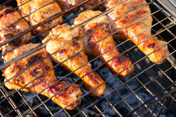 Grilled chicken meat, chicken legs on grill grid with smoke. Fried meat close up