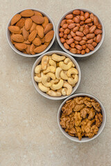 Nuts of different varieties, top view. Vertical photo for background, nuts in bowls on marble table top, place for text or design