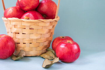 Close up view of red mature apples and basket full of apples with green leaves. Organic garden food