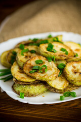 fried zucchini in circles with fresh herbs in a plate