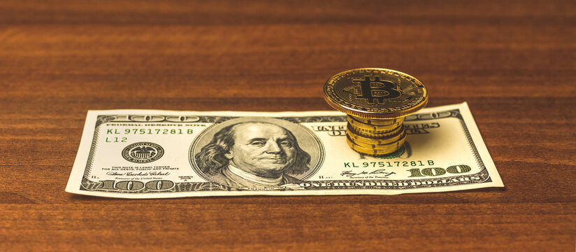 Cryptocurrency coin on a top of money, bitcon on a dollar bill on a wooden table, banner background