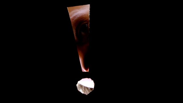 female eye peers into a hole exclamation mark in cardboard, concept to attract attention, caution, peep, watch out, industrial espionage