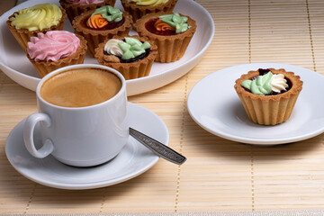 Morning aromatic coffee with colourful cupcakes with cream cakes on a white plate. Selective Focus