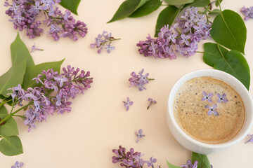 Lilac and purple flowers in a mug with coffee on a yellow modern background. Concept, heat, quench your thirst, summer vacation, there is a place for text