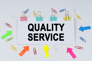 On the table there are paper clips and directional arrows, a sign that says - Quality Service