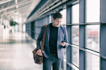 Mobile phone business man walking in airport with messenger bag using cellphone texting sms message...