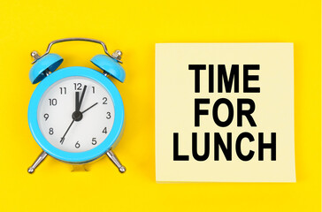 On a yellow background lie a clock and a sticker sheet with the inscription - TIME FOR LUNCH