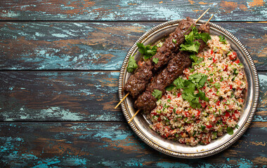 Middle eastern Turkish dinner with meat kebab and couscous salad tabbouleh on rustic metal plate on...