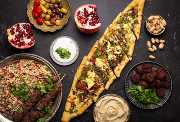 Various Turkish dishes: pide pizza, meat kebab with tabbouleh salad, falafel, hummus, olives,...