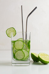 Fresh water infused with cucumbers, sprigs of mint and lime, with metal cocktail tubes, detox drink in a glass. Health care, fitness, healthy food concept.
