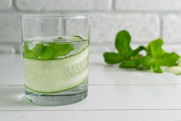 A glass of detox water infused with cucumber and mint, with ingredients. Health care, fitness, healthy food concept.